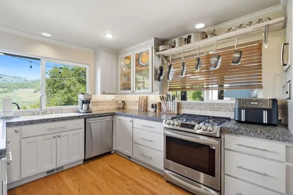 a kitchen with stainless steel appliances granite countertop a stove a sink and white cabinets
