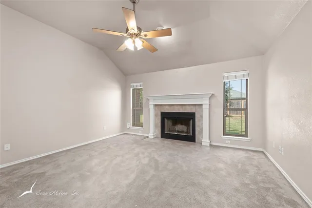 a view of an empty room with window and chandelier fan