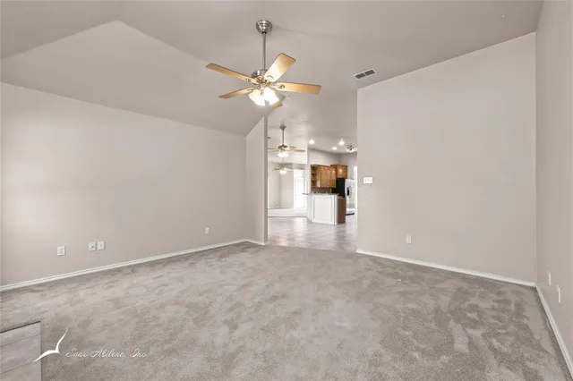 an empty room with chandelier fan and fireplace