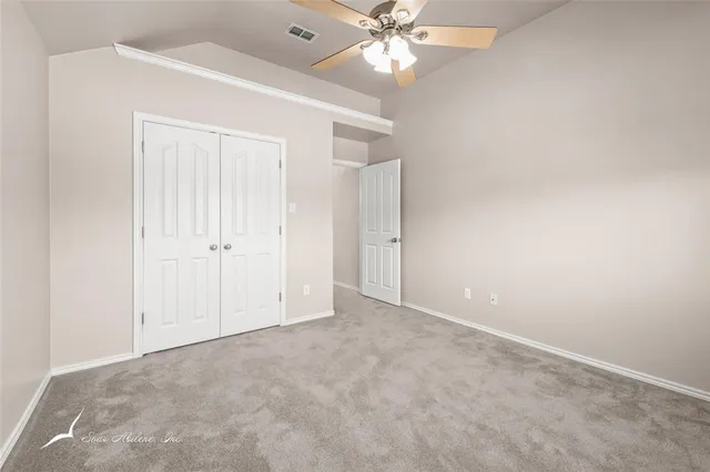 an empty room with windows and chandelier fan