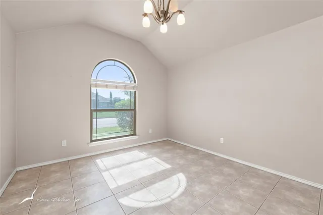 an empty room with windows and chandelier fan