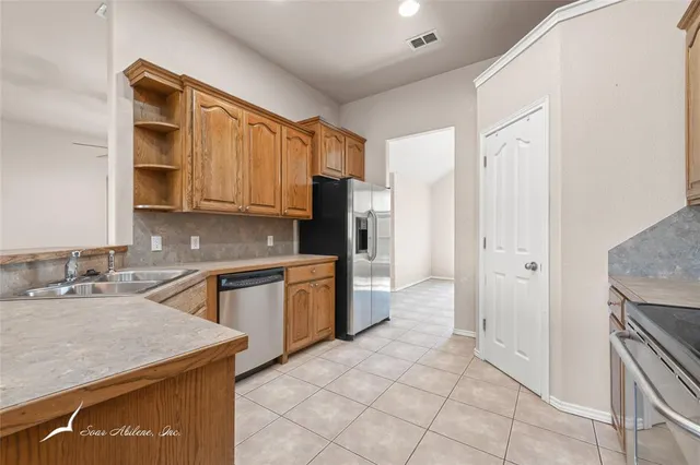 a large kitchen with stainless steel appliances granite countertop a stove top oven a sink dishwasher a dining table and chairs with wooden floor