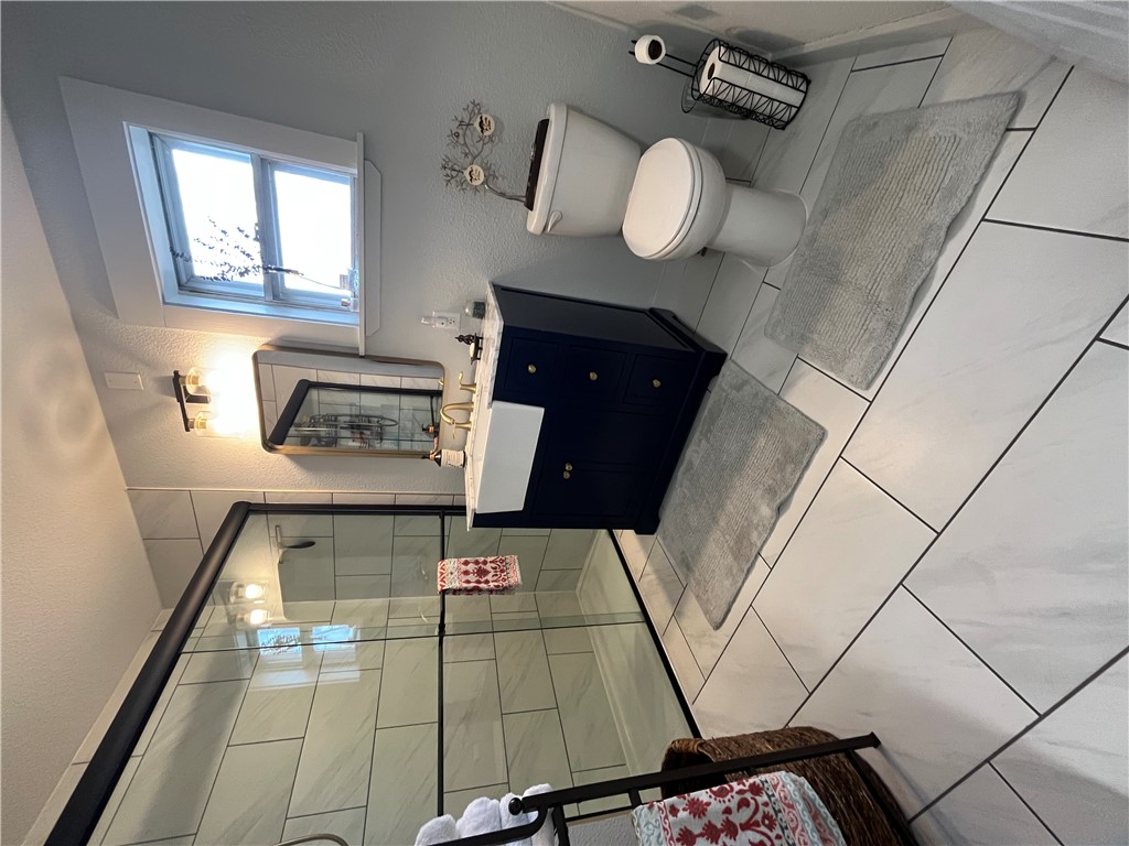 1102 North Travis Avenue Cameron, TX 76520 - Photo 10 of 48 Full bath with vanity, a textured wall, a stall shower, and a textured ceiling