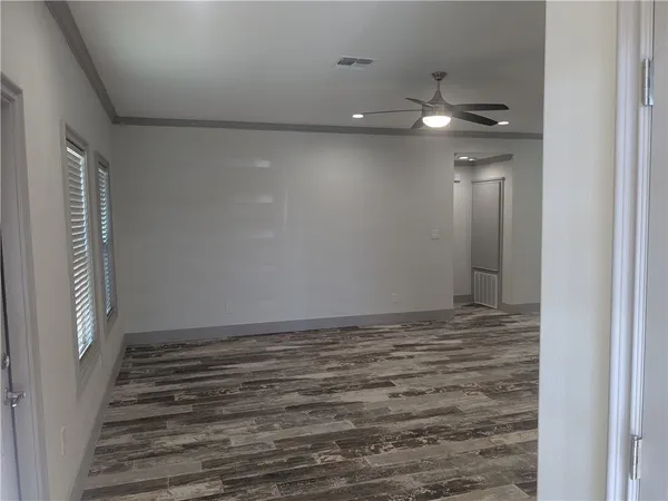a view of an empty room with wooden floor and staircase