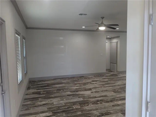 a view of an empty room with wooden floor and staircase