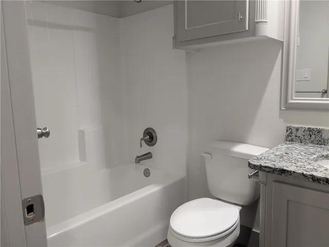 a bathroom with a granite countertop tub sink and mirror