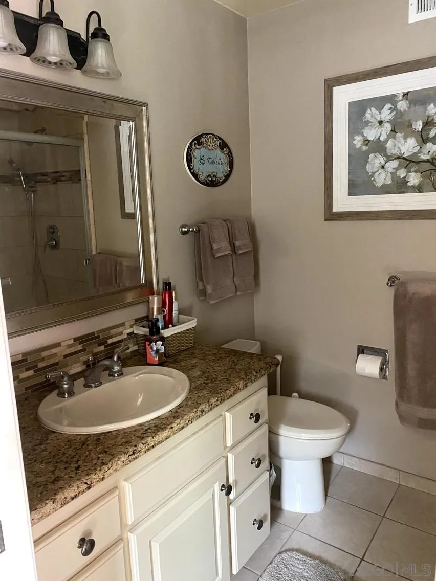 10835 Singletree Lane Spring Valley, CA 91978 - Photo 2 of 31 a bathroom with a granite countertop sink a toilet and a mirror