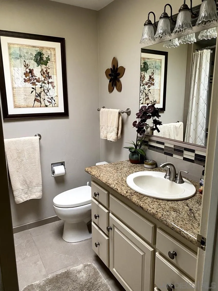 10835 Singletree Lane Spring Valley, CA 91978 - Photo 22 of 31 a bathroom with a granite countertop toilet a sink and mirror