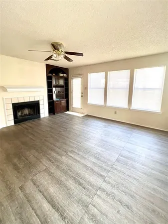 an empty room with fireplace cabinet and windows