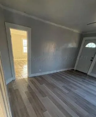 a view of an empty room and wooden floor and a window