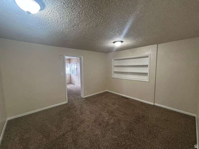 265 Rigdon Avenue, Unit 1 Salt Lake City, UT 84115 - Photo 7 of 15 Carpeted interior space featuring neutral wall paint and a built-in shelving unit