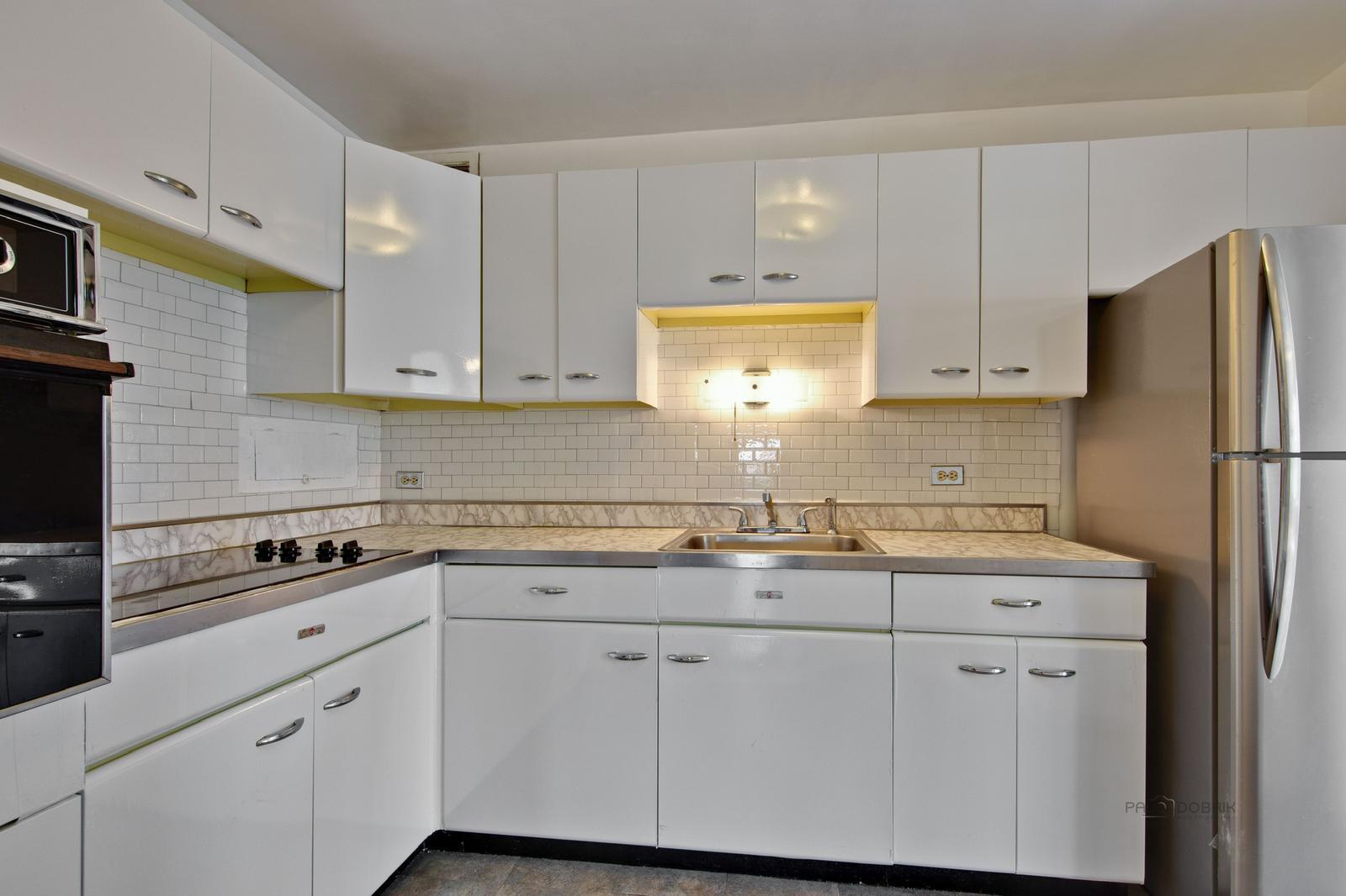 6157 North Sheridan Road, Unit 4M Chicago, IL 60660 - Photo 3 of 4 a kitchen with white cabinets and refrigerator
