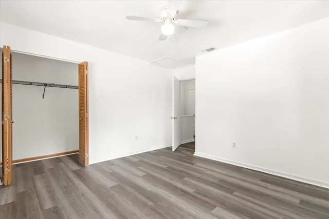 an empty room with wooden floor closet and ceiling fan