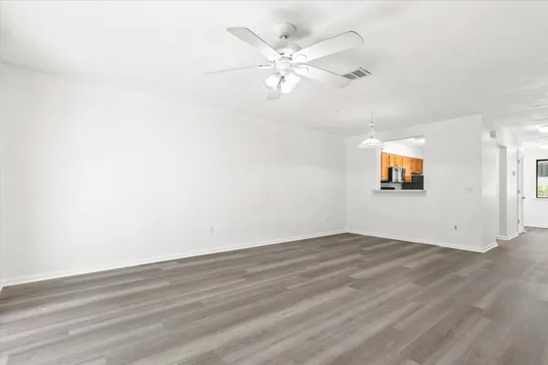 an empty room with wooden floor and windows
