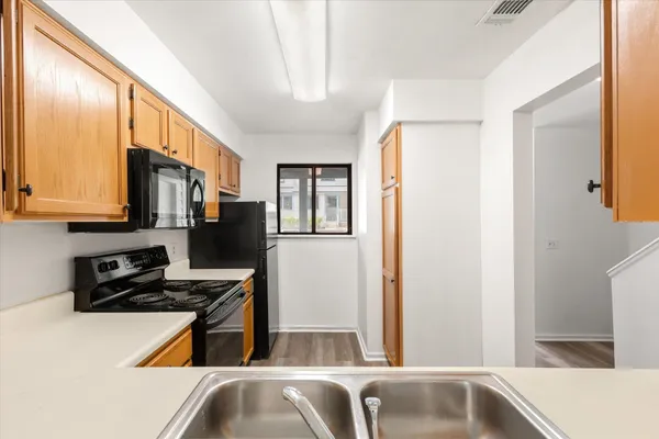 a kitchen with stainless steel appliances granite countertop a refrigerator a stove and a sink with wooden floor