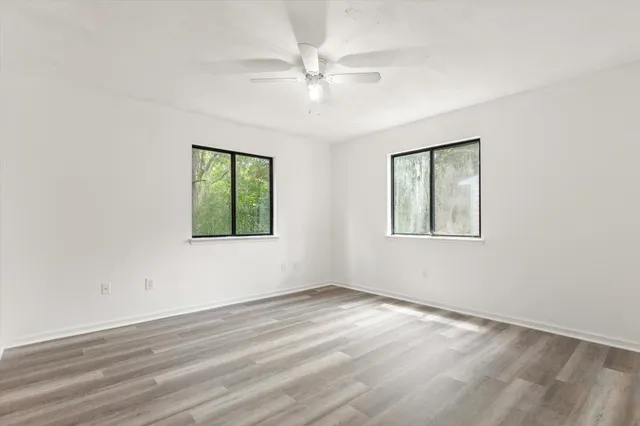 an empty room with wooden floor chandelier and windows