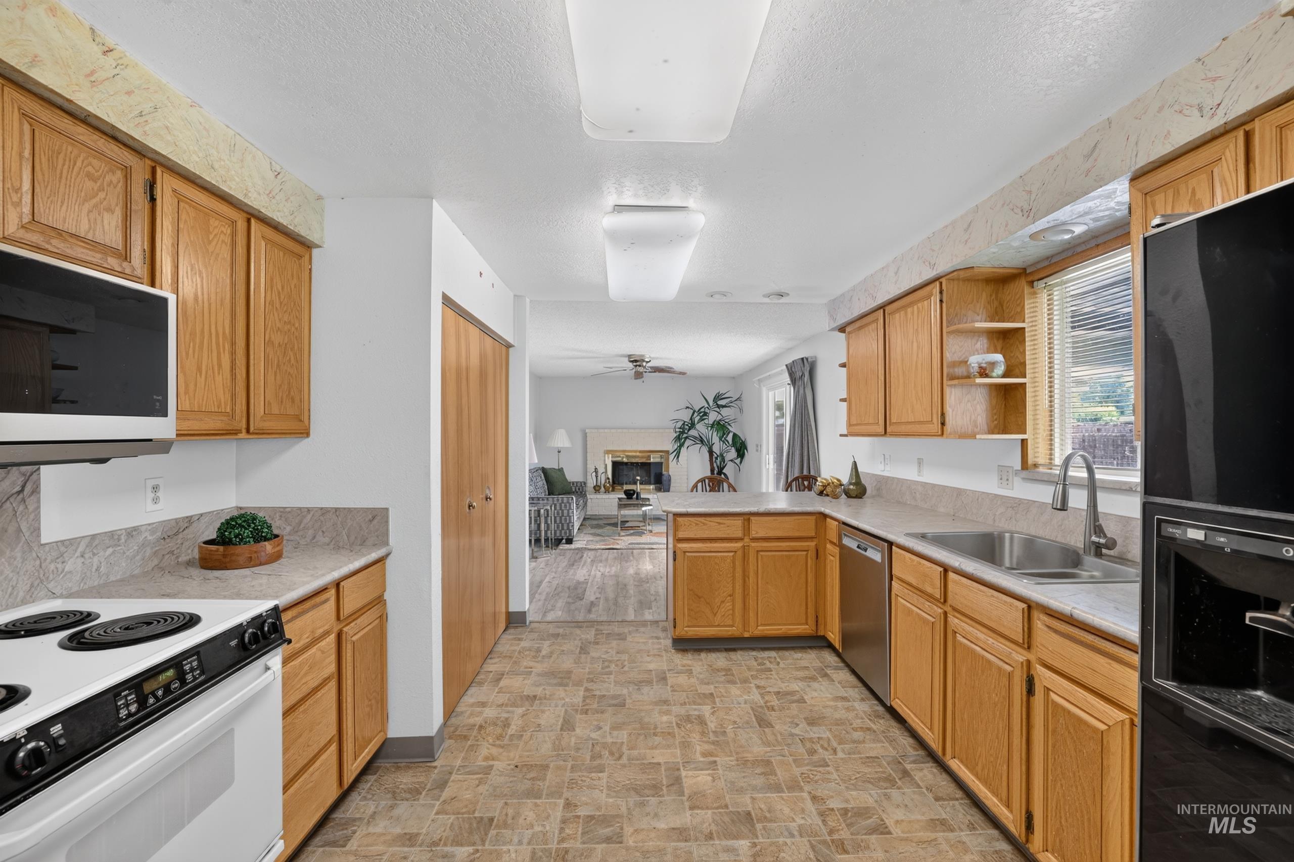 9055 West Highlander Road Boise, ID 83709 - Photo 14 of 39 U-shaped kitchen featuring wood cabinetry, integrated stainless steel dishwasher, stainless steel sink with a gooseneck faucet, and durable tile-finish flooring