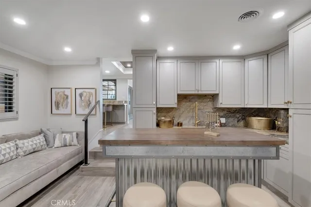 a kitchen with kitchen island granite countertop a stove a sink a refrigerator and white cabinets with wooden floor