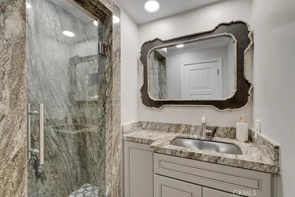 a bathroom with a granite countertop sink a mirror and shower