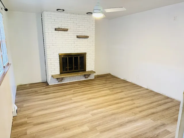 a view of an empty room with a fireplace and a window