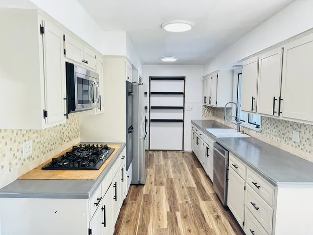 a kitchen with stainless steel appliances a sink stove and cabinets