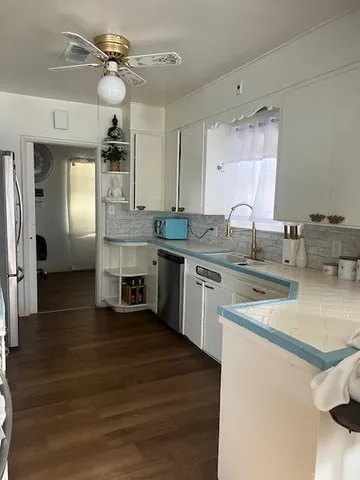 a kitchen with stainless steel appliances granite countertop a sink cabinets and wooden floor