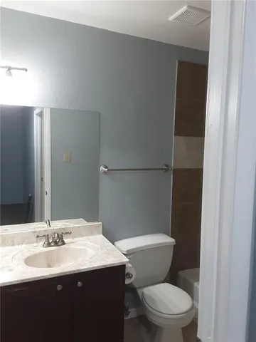 a bathroom with a granite countertop toilet sink and mirror