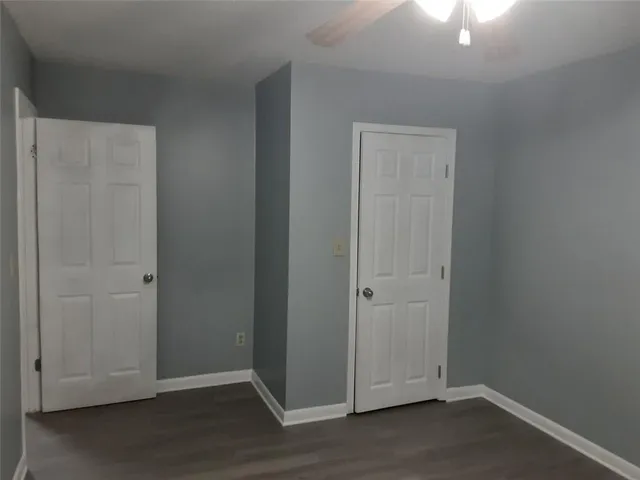 an empty room with wooden floor closet and windows