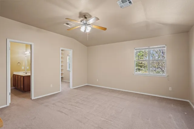 a view of an empty room with chandelier fan