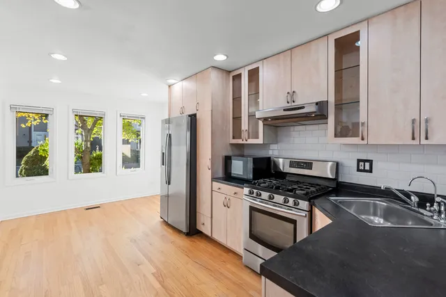 a kitchen with granite countertop a stove a sink dishwasher and a refrigerator with wooden floor