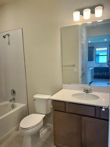 a bathroom with a sink a toilet a mirror a vanity and bathtub
