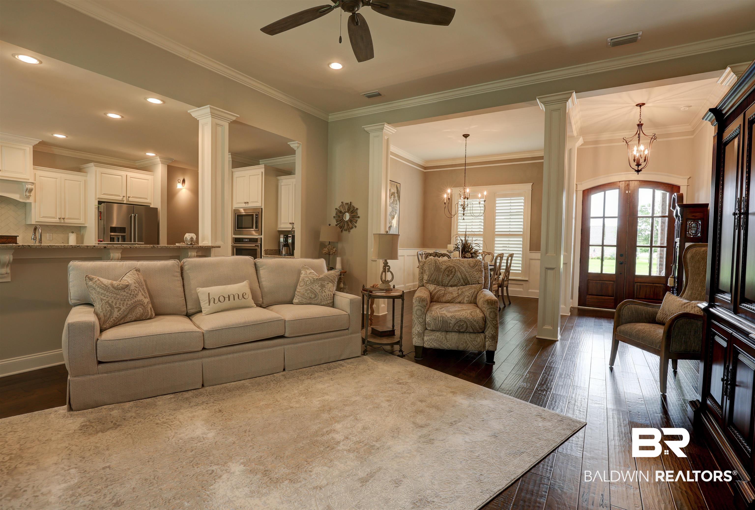 10588 Leesburg Pike Daphne, AL 36526 - Photo 8 of 29 Living room with decorative columns, dark wood-type flooring, ceiling fan with notable chandelier, and ornamental molding