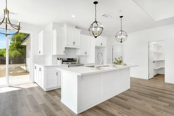 a large kitchen with stainless steel appliances a large center island attached withe living room