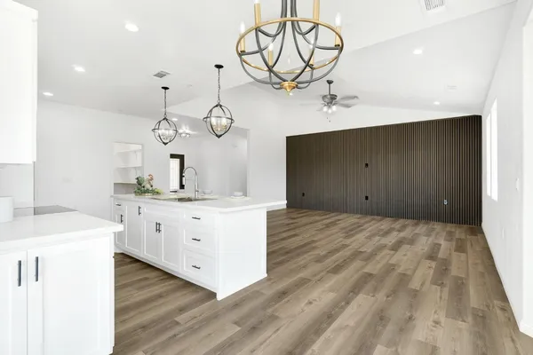 a large white kitchen with a large island wooden floor and stainless steel appliances