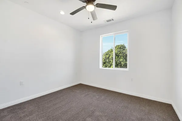an empty room with a window and a fan