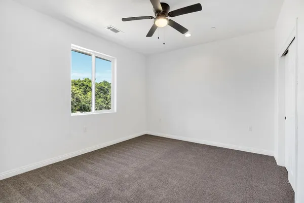 an empty room with a window and a ceiling fan