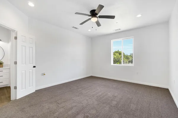 an empty room with a window and a ceiling fan