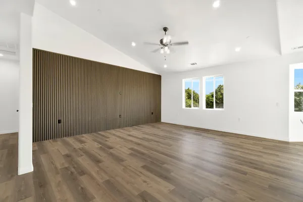 a view of an empty room with window and wooden floor