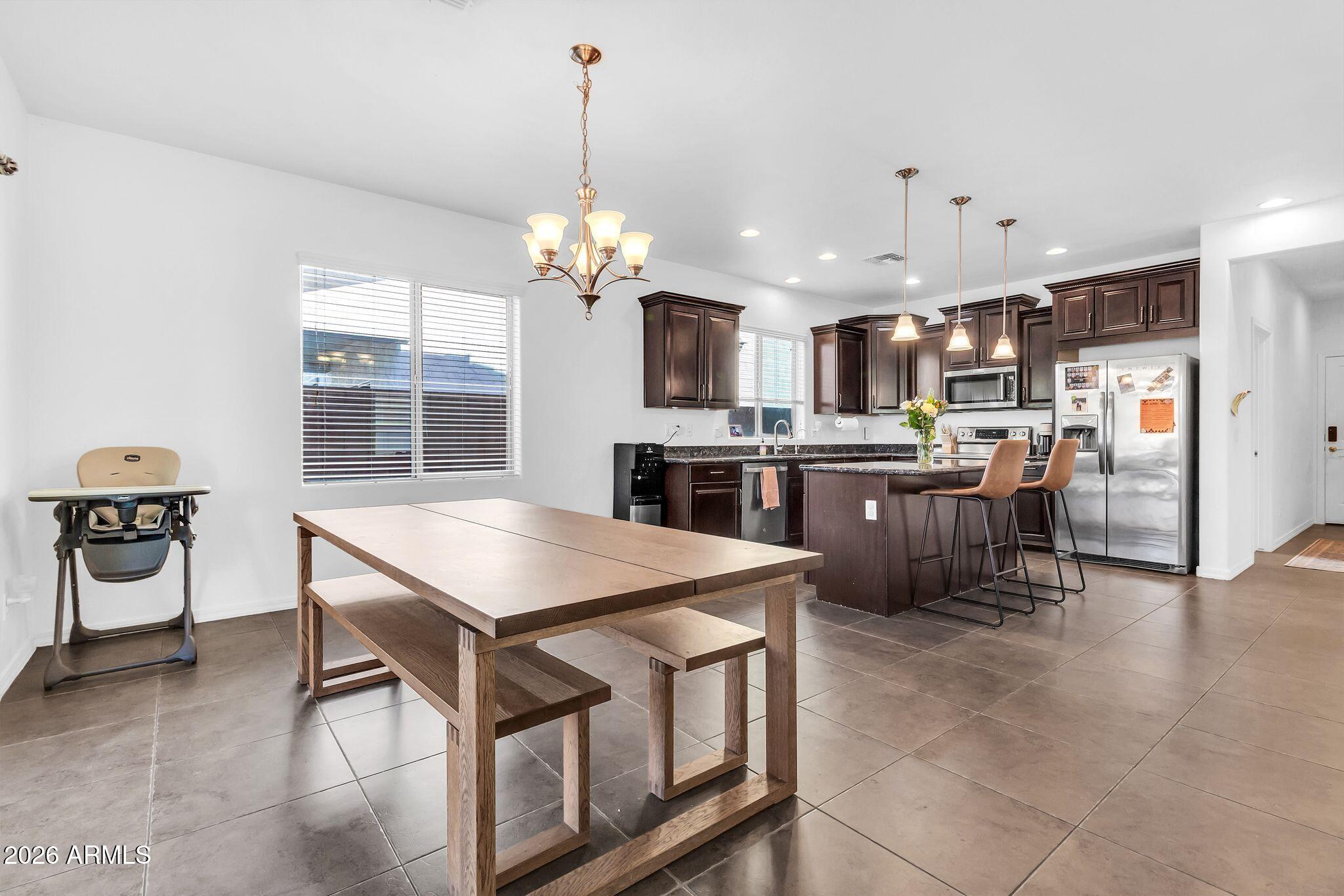 4120 South Butte Lane Gilbert, AZ 85297 - Photo 9 of 29 a kitchen with stainless steel appliances kitchen island a table chairs in it and wooden floors