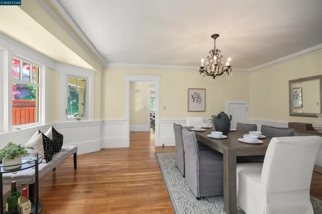 a dining room with wooden floor a chandelier a wooden table and chairs