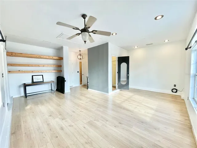 a view of an empty room with window and a ceiling fan