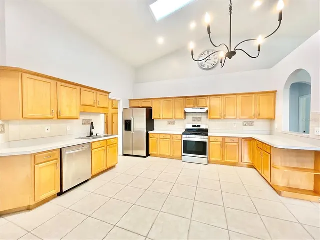 a large white kitchen with a large window cabinets and stainless steel appliances