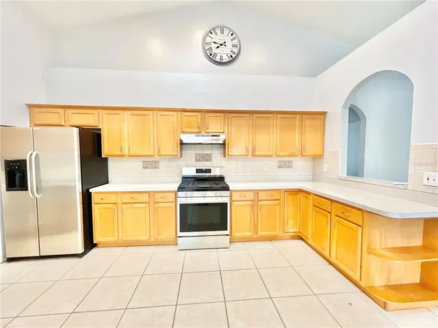 a large kitchen with stainless steel appliances granite countertop a stove a sink and a refrigerator