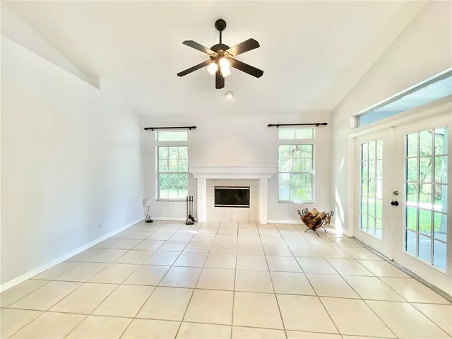a view of an empty room with window and chandelier fan