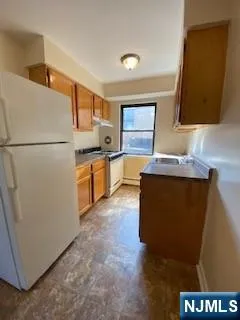a kitchen with granite countertop a refrigerator a sink a stove and dishwasher
