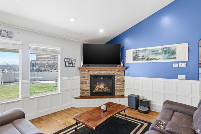 860 West 2980th Street South Logan, UT 84321 - Photo 7 of 38 Stone-clad fireplace with a wood mantle and hearth, recessed lighting, wood-finish flooring, two large windows, and white wainscoting