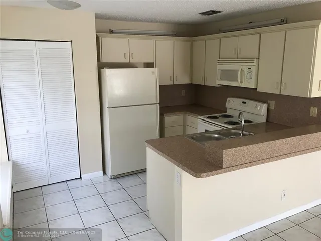 a kitchen with a sink a refrigerator and cabinets