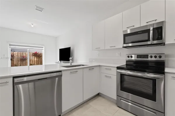 a kitchen with kitchen island a white cabinets and refrigerator