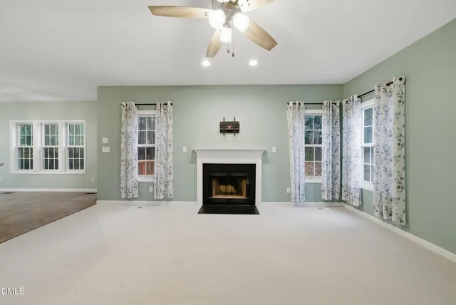 a view of an empty room with a fireplace and a ceiling fan