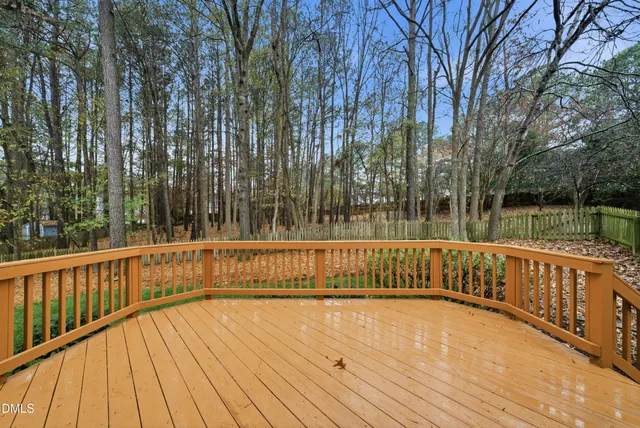 a view of deck with large trees and wooden fence